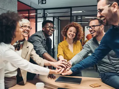 Diverse group of employees embracing hands 