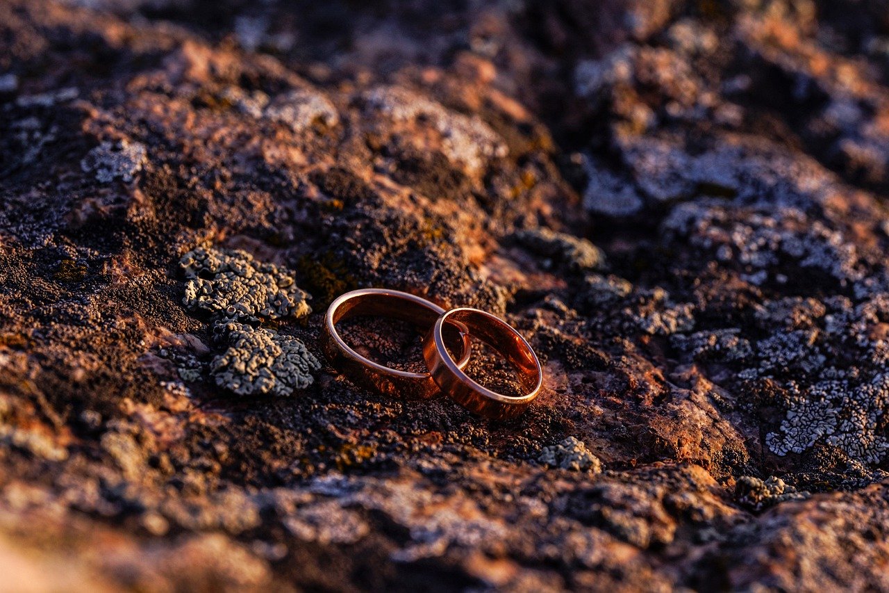 Two rose gold rings together on top of a rock 